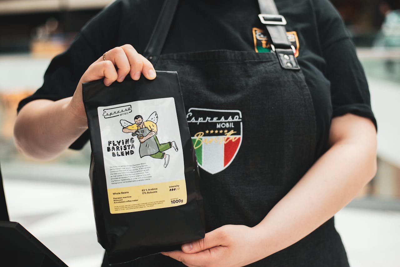 Close-up of a person showcasing Flying Barista Blend coffee packaging.