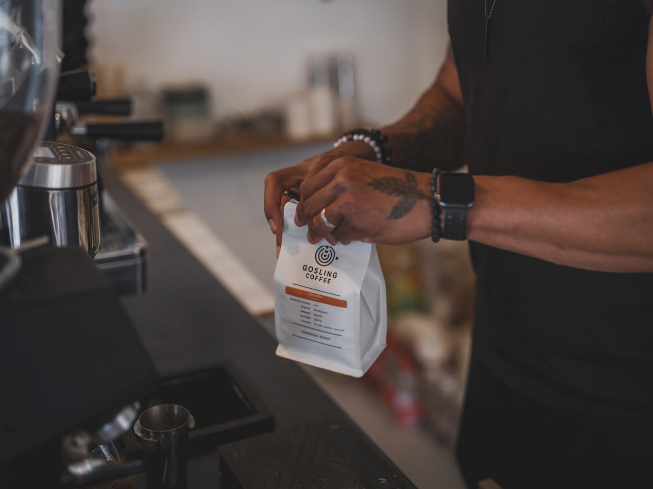 Barista showcasing Gosling coffee bag in a modern cafe setting.